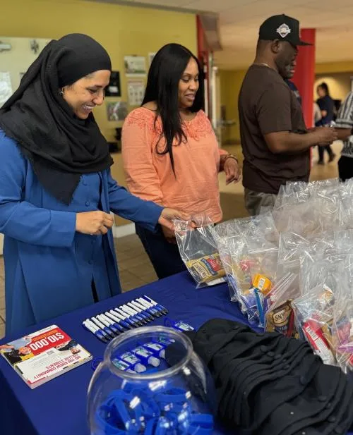 Three college students select giveaways off a table